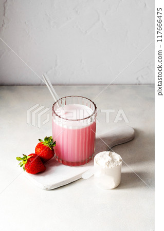 Pink strawberry protein drink shake, and protein powder in a scoop. Food supplement. Pink strawberry protein drink shake, and protein powder in a scoop. Food supplement. 117666475