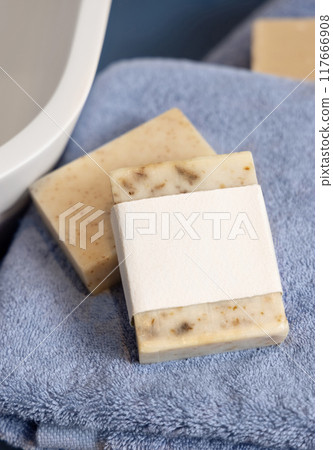 Soap bars with blank label on blue towels near vessel sink in bathroom, packaging mockup Soap bars with blank label on blue towels near vessel sink in bathroom, packaging mockup 117666908