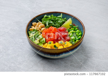 Top view of a colorful salmon poke bowl with fresh vegetables and rice, presented 117667102