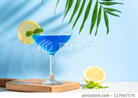 Blue summer cocktail with lemon and palm leaf Blue summer cocktail with lemon and palm leaf 117667578