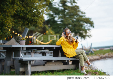 Young woman listens to music, audiobook. Communication in social networks. Lifestyle concept. Young woman listens to music, audiobook. Communication in social networks. Lifestyle concept. 117667800