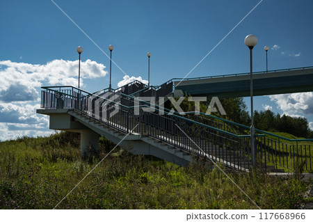 A pedestrian bridge over the highway. Steps for climbing the bridge A pedestrian bridge over the highway. Steps for climbing the bridge 117668966