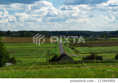 An asphalt road in the distance between fields. Thick clouds over the road An asphalt road in the distance between fields. Thick clouds over the road 117668968