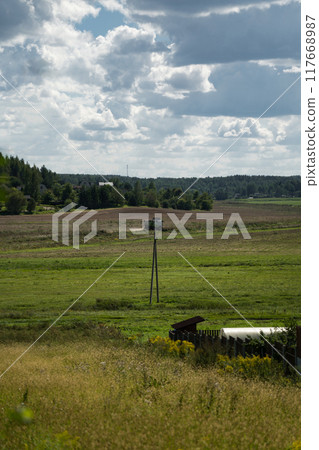 A combine harvester in the distance reaps wheat in a field 117668987