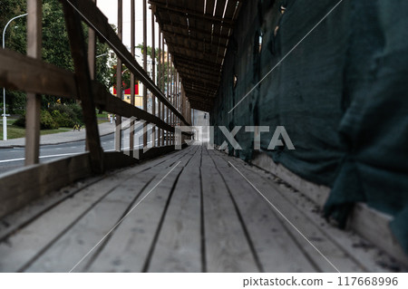 A wooden, temporary pedestrian crossing past the construction site. Evening City 117668996