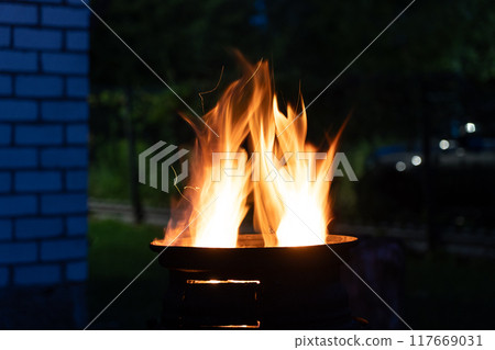 The fire is burning in the grill. A bonfire burning at night The fire is burning in the grill. A bonfire burning at night 117669031