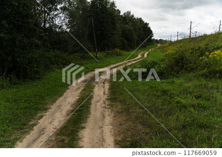 A rural, dirt road leading up. Cloudy sky 117669059