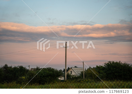 The support of power lines against the background of an orange sunset sky 117669123