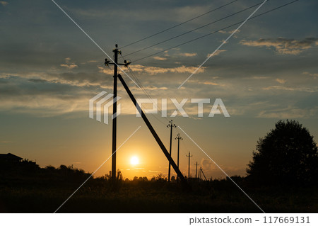 Supports of power lines extending into the distance into the field. Eevening Supports of power lines extending into the distance into the field. Eevening 117669131