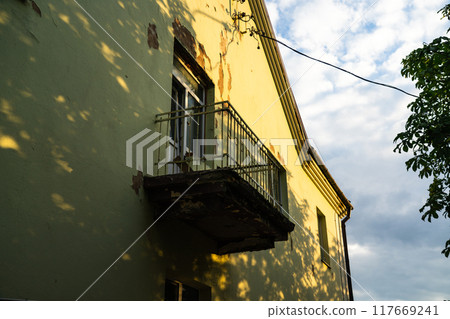 Balcony with access to the street, in an old house, with peeling plaster Balcony with access to the street, in an old house, with peeling plaster 117669241