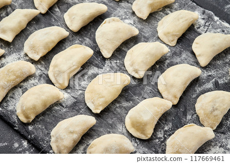 Freshly prepared homemade dumplings ready for cooking, showcasing traditional culinary skills Freshly prepared homemade dumplings ready for cooking, showcasing traditional culinary skills 117669461