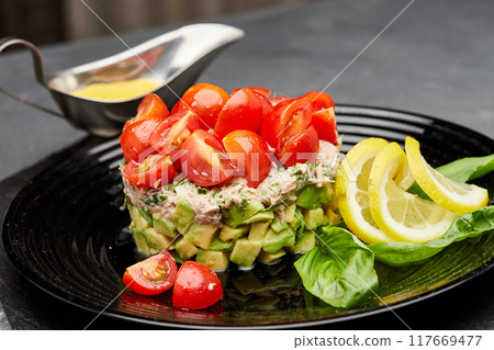 Fresh avocado and tuna salad topped with cherry tomatoes, garnished with lemon slices and basil Fresh avocado and tuna salad topped with cherry tomatoes, garnished with lemon slices and basil 117669477