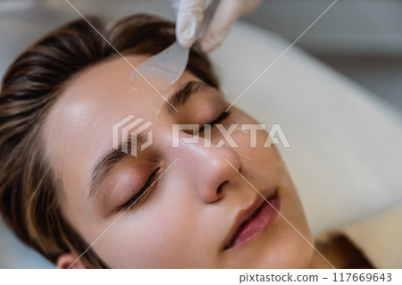 Woman receiving facial treatment at a skincare clinic in daylight 117669643