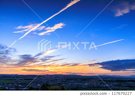 從京都府最南端的木津川市城山台眺望的夜景 凝結尾跡和夕陽的天空劃過天空 在俯瞰木津川町的山上#11。 117670227