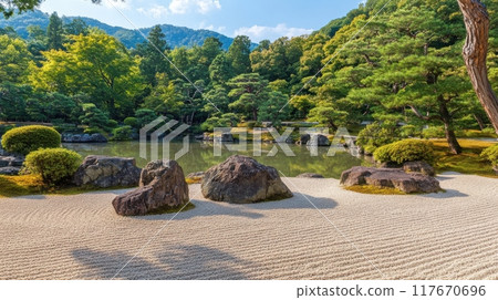 A tranquil view of a Zen garden in Kyoto with raked sand, rocks, and lush greenery under a clear sky, creating a serene and meditative atmosphere. 117670696