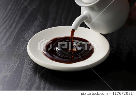 Soy sauce poured into a plate 117672051