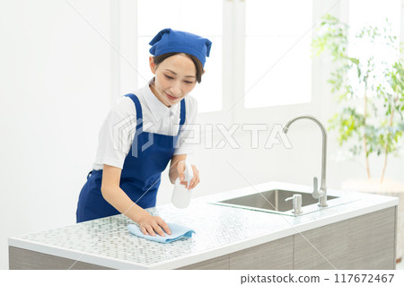 A woman from a housekeeping service cleaning the kitchen A woman from a housekeeping service cleaning the kitchen 117672467