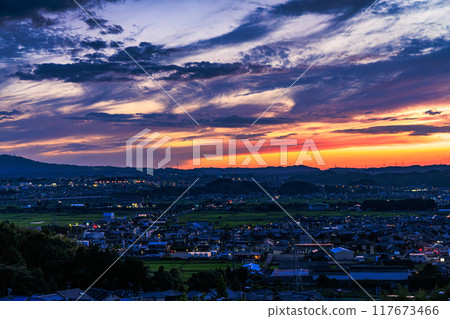 Evening view from Shiroyamadai in Kizugawa City, the southernmost part of Kyoto Prefecture. Sunset on the mountainside and the town lit up. On a hill overlooking the town of Kizu #2 117673466