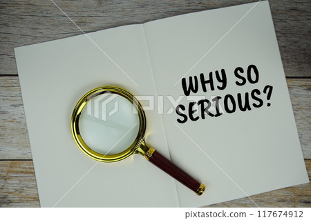 Why so Serious? text on notebook page with magnifying glass top view on wooden background 117674912
