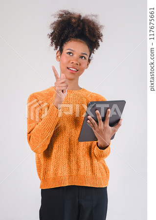 Smiling african american woman hand holding tablet and pointing upward. Isolated on white background. Smiling african american woman hand holding tablet and pointing upward. Isolated on white background. 117675661