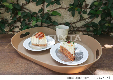 carrot cake with cream and walnut topping ,caramel macadamia cheesecake and hot tea 117675961