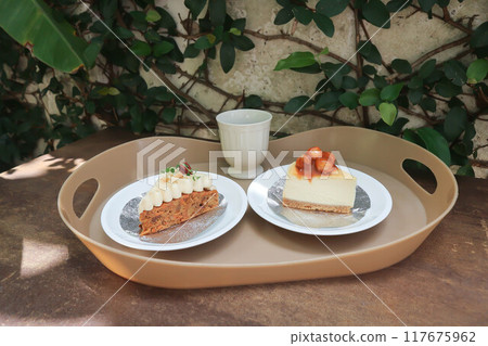 carrot cake with cream and walnut topping ,caramel macadamia cheesecake and hot tea 117675962