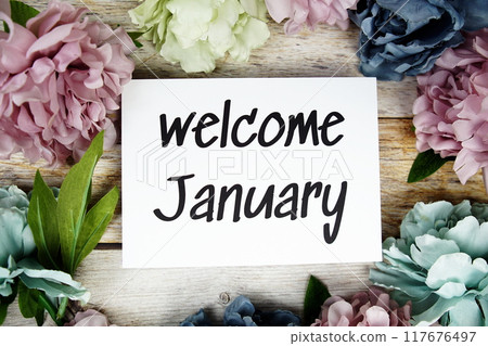 Welcome January text on paper card with flowers frame top view on wooden background Welcome January text on paper card with flowers frame top view on wooden background 117676497