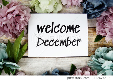 Welcome December text on paper card with flowers frame top view on wooden background Welcome December text on paper card with flowers frame top view on wooden background 117676498