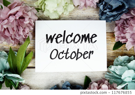 Welcome October text on paper card with flowers frame top view on wooden background 117676855