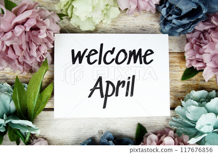 Welcome April text on paper card with flowers frame top view on wooden background Welcome April text on paper card with flowers frame top view on wooden background 117676856