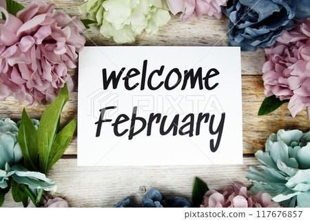Welcome February text on paper card with flowers frame top view on wooden background Welcome February text on paper card with flowers frame top view on wooden background 117676857