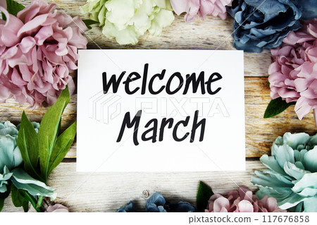 Welcome March text on paper card with flowers frame top view on wooden background Welcome March text on paper card with flowers frame top view on wooden background 117676858