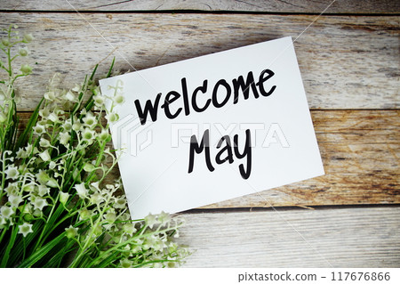 Welcome May text on paper card with flowers frame top view on wooden background 117676866