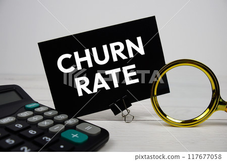 Churn Rate text message with calculate and magnifying glass on wooden background 117677058