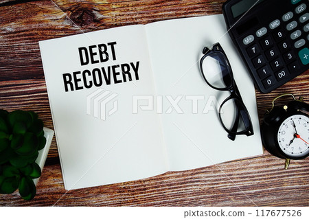 Debt Recovery text on note page with alarm clock and calculator top view on wooden background Debt Recovery text on note page with alarm clock and calculator top view on wooden background 117677526