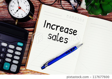 Increase sales text on note page with alarm clock and calculator top view on wooden background Increase sales text on note page with alarm clock and calculator top view on wooden background 117677600