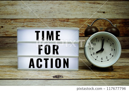 Time for Action text on LED lightbox with alarm clock on wooden background 117677796
