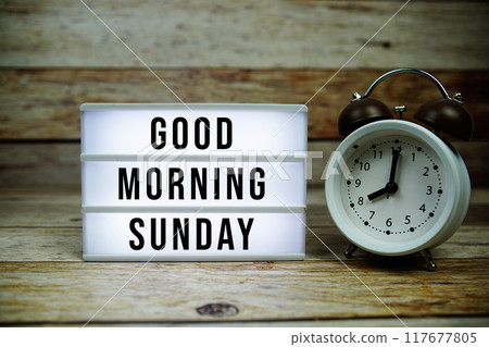 Good Morning Sunday text on LED lightbox with alarm clock on wooden background Good Morning Sunday text on LED lightbox with alarm clock on wooden background 117677805