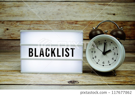 Blacklist text on LED lightbox with alarm clock on wooden background, Business and Money concept Blacklist text on LED lightbox with alarm clock on wooden background, Business and Money concept 117677862
