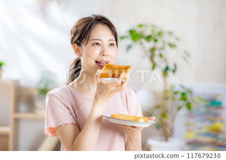 Young woman eating toast 117679238