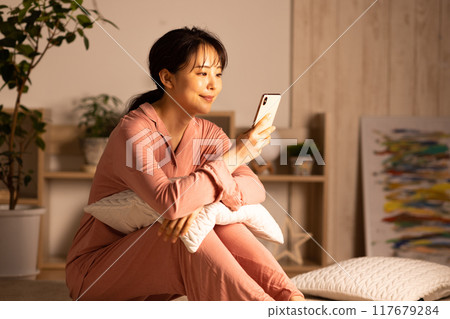 Young woman looking at her smartphone at night 117679284