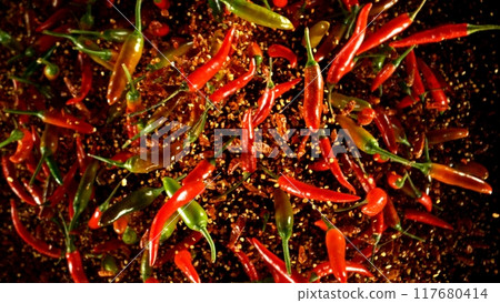 Group of coloured chilli peppers flying on black background. 117680414