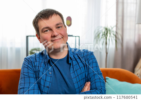 Portrait of happy Caucasian man sitting on couch looking at camera and smiling relaxing at home 117680541