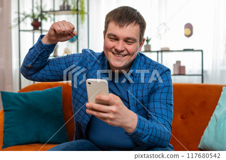Surprised excited man holding smartphone reading good news amazed by online bet bid game win victory Surprised excited man holding smartphone reading good news amazed by online bet bid game win victory 117680542