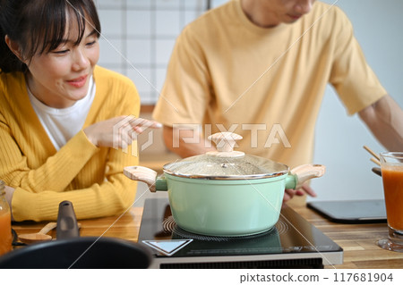 Young cheerful couple cooking together making dinner or lunch in a cozy kitchen Young cheerful couple cooking together making dinner or lunch in a cozy kitchen 117681904