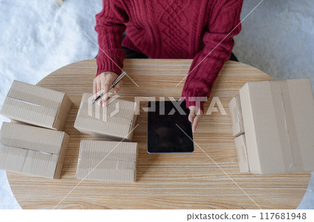 woman, online seller, using a tablet computer efficiently manages customer orders and delivery through the e-commerce platform 117681948