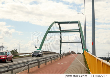 A bridge spans over a road with a dedicated bicycle lane, showing a car driving across and traffic moving smoothly. cycling infrastructure into urban planning and road usage A bridge spans over a road with a dedicated bicycle lane, showing a car driving across and traffic moving smoothly. cycling infrastructure into urban planning and road usage 117682216