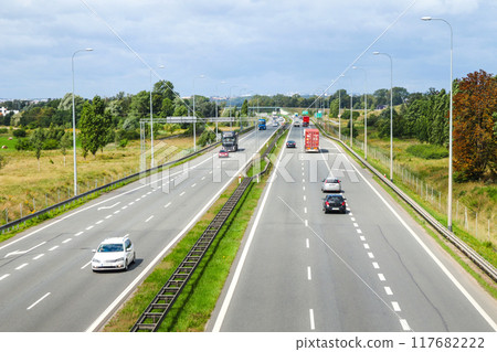 Aerial view of a highway with multiple lanes, showcasing the flow of traffic, including cars and trucks. highlighting the movement and organization of vehicles on a major roadway 117682222
