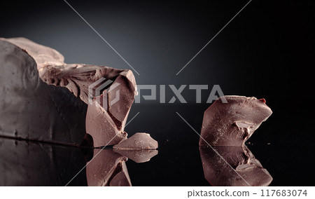 Large piece of dark bitter chocolate on a black reflective background. 117683074
