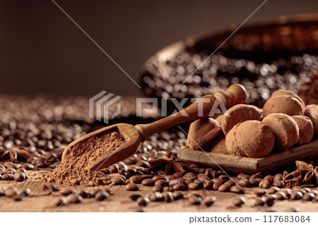 Chocolate truffles and a wooden spoon with cacao powder. 117683084
